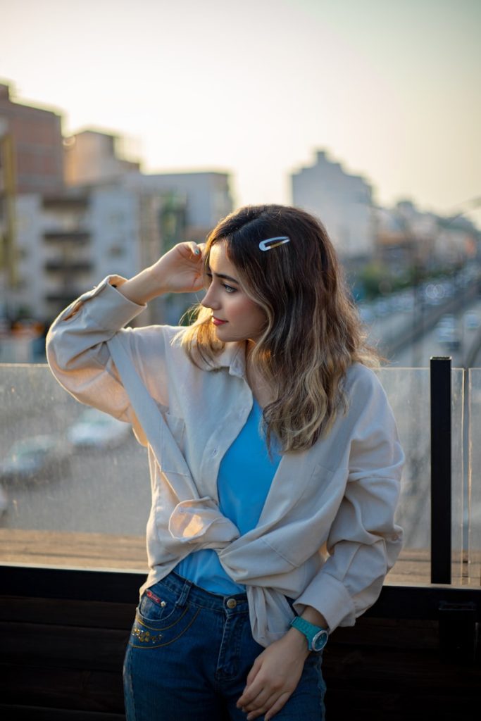 A woman standing in front of a window with her hand on her head